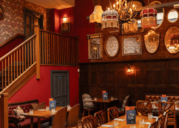The interior of a Stamford restaurant with wooden panelling, red walls and warm lighting